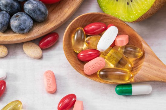 Closeup shot of fresh fruits with different medicine on a wooden spoon A closeup shot of fresh fruits with different medicine on a wooden spoon