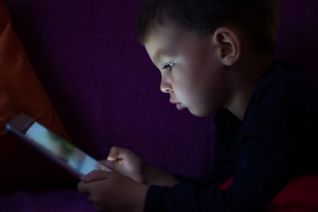 Cute kid with tablet in the dark.