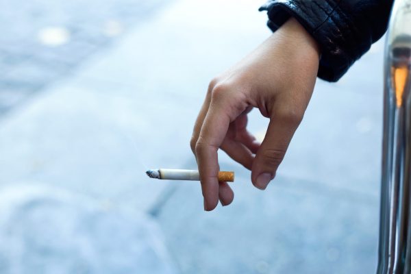 Close up of womans hand with cigarette in the street.