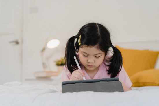Young Asian girl drawing at home. Asia japanese woman child kid Young Asian girl drawing at home. Asia japanese woman child kid relax rest fun happy draw cartoon in sketchbook before sleep lying on bed, feel comfort and calm in bedroom at night concept.
